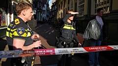 Funkcjonariusze policji stoją za odgrodzonym obszarem po pchnięciu nożem w pobliżu placu Dam w centrum Amsterdamu.