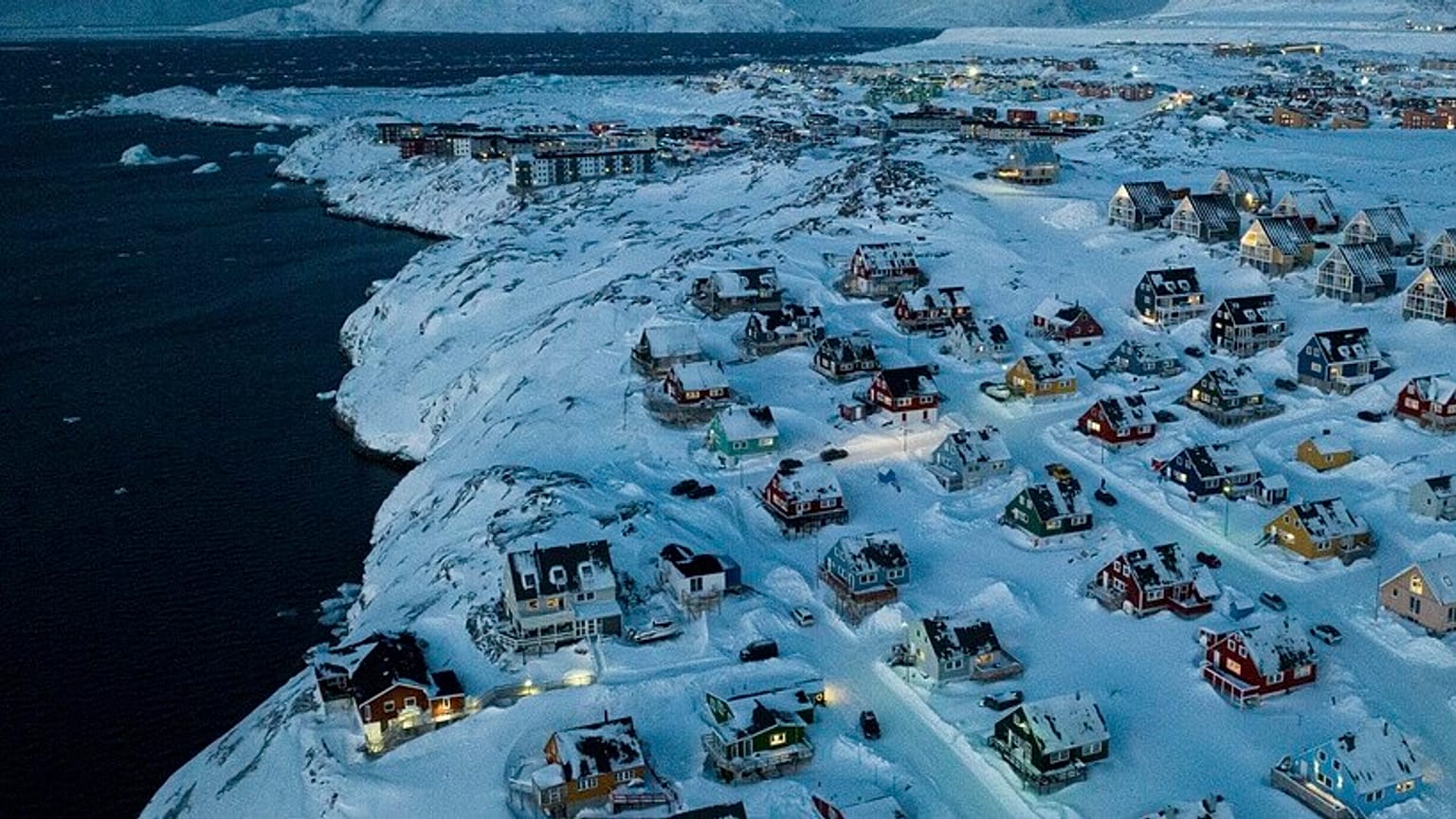 Hóval borított házak láthatók a grönlandi Nuukban, egy tengeri öböl partján, 2025. március 7-én, pénteken.