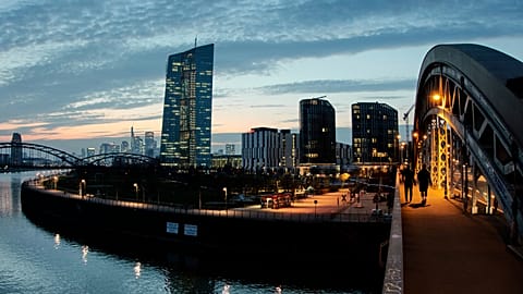 People walk on a bridge over the river Main near the European Central Bank in Frankfurt, Germany. 25 March 2025.