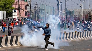 A pro-monarchist group hurls a tear gas shell at police officers during a protest in Kathmandu, 28 March, 2025