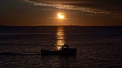 Ein Fischerboot wird während der partiellen Sonnenfinsternis im kanadischen Halifax. 29. März 2025, als Silhouette dargestellt.