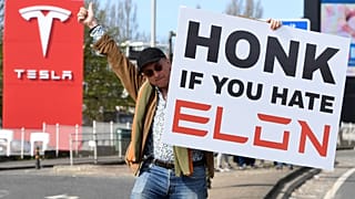 Protestujący trzyma transparent, biorąc udział w Akcji Tesla Takedown w pobliżu salonu Tesli w Londynie, 29 marca 2025 r.