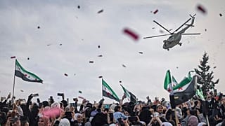 Конфетти и цветы сбрасывают с военного вертолета на толпу людей во время празднования победы повстанческих сил над армией Асада в Идлибе, Сирия, 28 марта 2025 г.