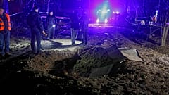 Polizeibeamte betrachten einen von einer Drohne verursachten Krater in der Nähe von Wohnhäusern nach dem russischen Nachtangriff in Charkiw, Ukraine, am späten Samstag, 29. März 2025.