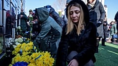 Menschen legen während einer Zeremonie zum dritten Jahrestag der russischen Invasion in der Ukraine in Bucha, Ukraine, am 24. Februar 2025 Blumen an einer Gedenkstätte für getötete Zivilisten nieder.