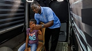 Rita Zaansuma-Naporo, de 9 años, acompañada por su padre, asiste a una prueba en directo de la tecnología de telemedicina en 3D en el hospital de Koforidua, Ghana.