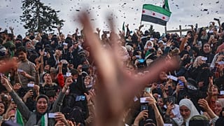 Des bonbons et des fleurs sont largués d'un hélicoptère militaire sur la foule lors d'une célébration marquant le 10e anniversaire de la victoire sur l'armée de Bachar al-Assad à Idlib.