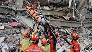 Mitglieder eines chinesischen Such- und Rettungsteams transportieren eine schwangere Überlebende aus einem eingestürzten Gebäude nach einem Erdbeben in Mandalay, 31. März 2025