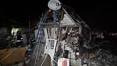 Trabalhadores de resgate limpam os escombros de uma casa destruída num ataque russo a um bairro residencial de Kharkiv, Ucrânia, sábado, 29 de março de 2025. 
