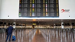Um homem com bagagem em frente a um painel de partidas cheio de cancelamentos, durante uma greve geral, no Aeroporto Internacional de Bruxelas.