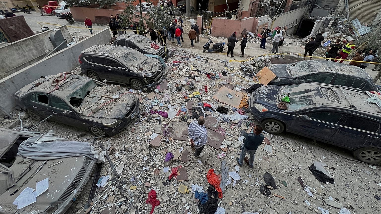 Moradores libaneses reúnem-se em torno de carros danificados no local onde um ataque aéreo israelita atingiu um edifício em Dahiyeh, um subúrbio do sul de Beirute, Líbano, 1 de abril de 2025