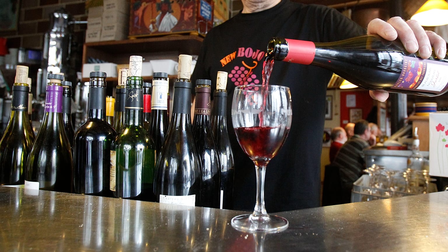 Un camarero sirve una copa de vino a un cliente en un bar.