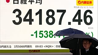 As pessoas passam por um painel eletrónico que mostra as perdas do dia do índice Nikkei 225 do Japão numa empresa de valores mobiliários, na quinta-feira, 3 de abril de 2025, em Tóquio.