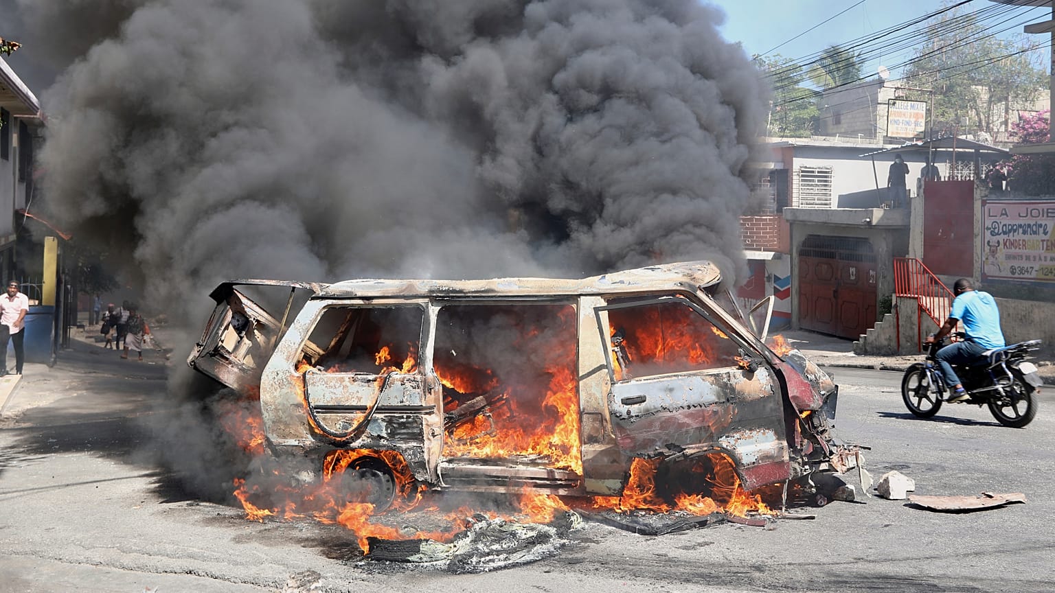 Ein Motorradfahrer fährt an einem brennenden Auto vorbei während eines Protests gegen die Unsicherheit in Port-au-Prince, Haiti, am Mittwoch, den 2. April 2025