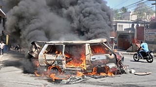 Ein Motorradfahrer fährt an einem brennenden Auto vorbei während eines Protests gegen die Unsicherheit in Port-au-Prince, Haiti, am Mittwoch, den 2. April 2025