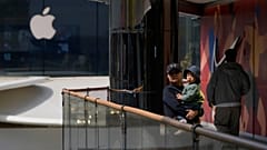 Eine Frau mit einem Kind steht in der Nähe von Apple- und Nike-Geschäften in Peking, China. 4. April 2025.