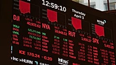 Ein Bildschirm zeigt Finanznachrichten an, während Händler auf dem Parkett der New York Stock Exchange in New York arbeiten, Donnerstag, 3. April 2025