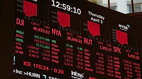 A screen displays financial news as traders work on the floor at the New York Stock Exchange in New York, Thursday, April 3, 2025
