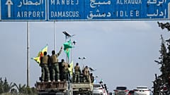 مقاتلون أكراد يقفون على مركباتهم أثناء انسحابهم من مدينة حلب شمال سوريا في إطار اتفاق مع الحكومة السورية الانتقالية، في حلب، سوريا، الجمعة، 4 أبريل/نيسان 2025
