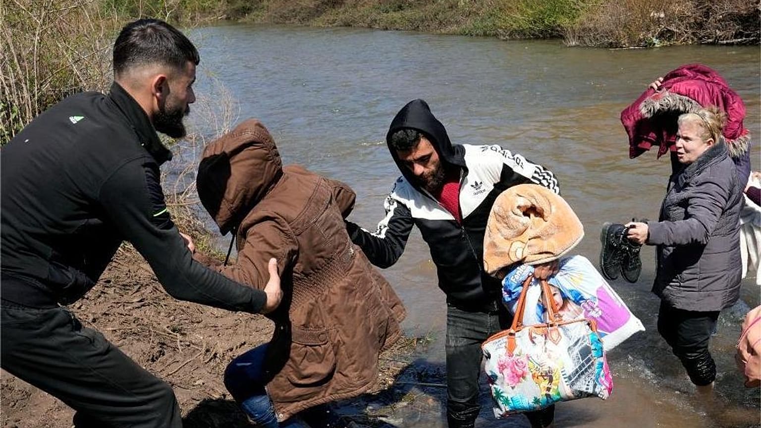 Famiglie siriane attraversano un fiume al confine tra Siria e Libano settentrionale nel villaggio di Hiker al-Daher, nel governatorato di Akkar, martedì 11 marzo 2025