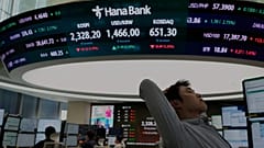 Ένας συναλλασσόμενος αντιδρά κοντά σε μια οθόνη που δείχνει τον σύνθετο δείκτη τιμών μετοχών της Κορέας (KOSPI)