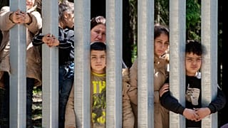 Asylum seekers outside a wall that Poland has built on its border with Belarus, in Bialowieza 