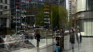 Peatones y edificios de oficinas se reflejan en el escaparate de una agencia de valores en Pekín. el 7 de abril de 2025.