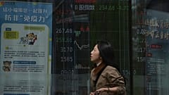 Bir kadın, 7 Nisan 2025'te Pekin'de bir aracı kurumda hisse senedi işlem endeksini gösteren elektronik bir panonun yanında yürüyor. 