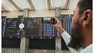مستثمر يلتقط صورة بهاتفه لمؤشرات السوق في بورصة كراتشي- باكستان. 7 أبريل 2025