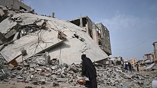 امرأة تنظر إلى منزل الصحفي إسلام مقداد المدمر، حيث قُتلت مع ابنها وخمسة من أفراد عائلتها في غارة للجيش الإسرائيلي في خان يونس، جنوب قطاع غزة، الأحد، 6 أبريل/نيسان 2025. 
