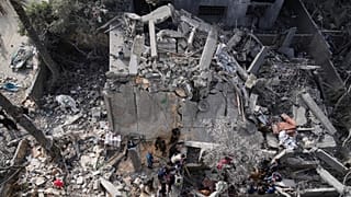 Palestinianos procuram sobreviventes entre os escombros de um edifício destruído por um ataque aéreo israelita em Deir al-Balah, 7 de abril de 2025