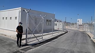 A police officer stands guard at the new closed monitored facility for migrants and refugees in Samos, 1 October, 2021
