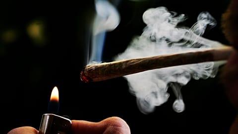 A regular user of soft drugs lights a marijuana joint in a coffee shop in Amsterdam, 24 June, 2008 
