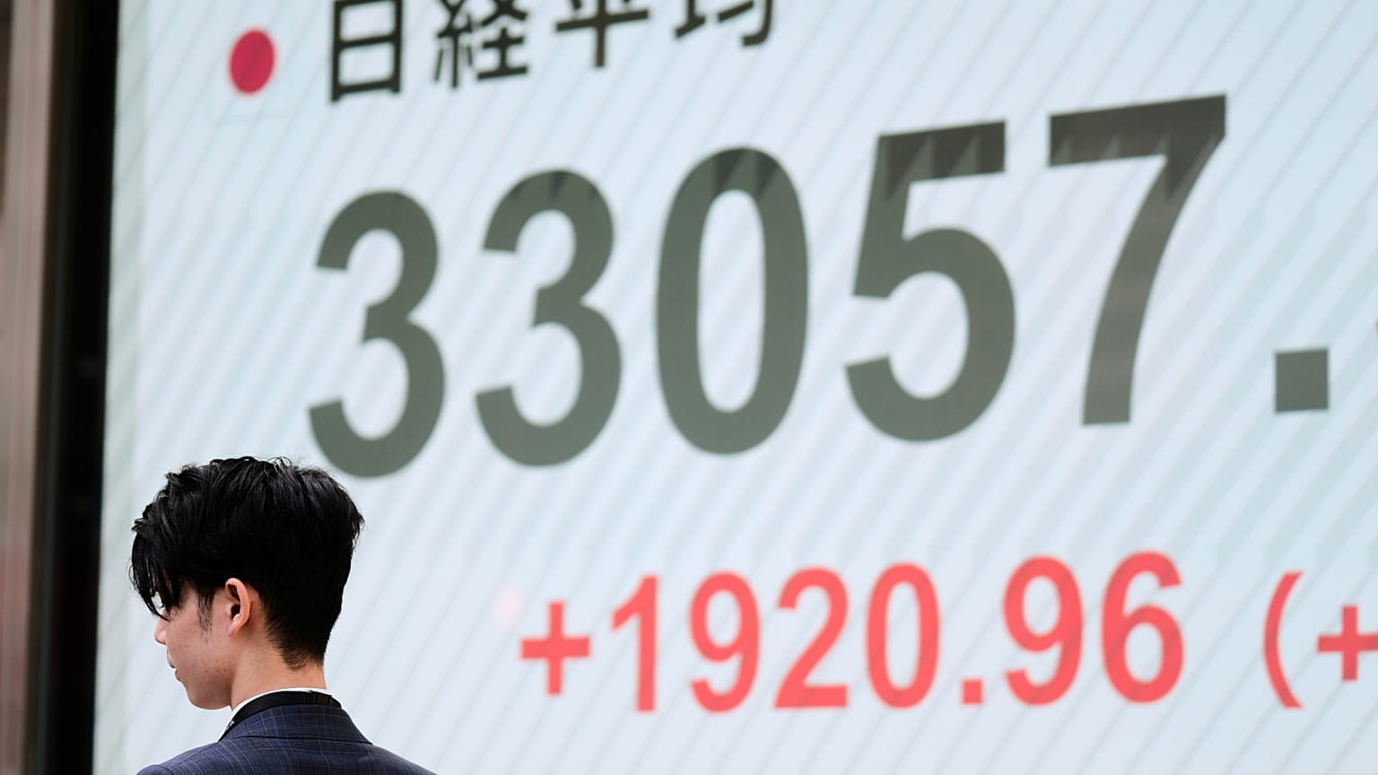 Um homem passa por monitores que mostram o índice Nikkei 225 do Japão numa empresa de valores mobiliários em Tóquio, terça-feira, 8 de abril de 2025. 