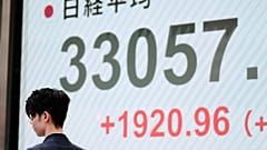 Bir adam, 8 Nisan 2025 Salı günü Tokyo'daki bir menkul kıymetler firmasında Japonya'nın Nikkei 225 endeksini gösteren monitörlerin yanında yürüyor. 