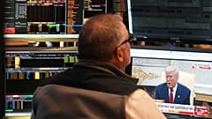 Präsident Donald Trump ist im Fernsehen zu sehen, während Händler auf dem Parkett der New York Stock Exchange in New York arbeiten, Montag, 7. April 2025.