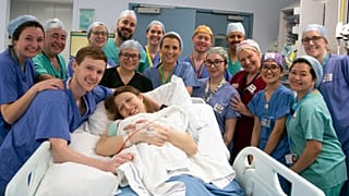 Die Davidson-Eltern lächeln mit ihrem neugeborenen Baby und dem medizinischen Team.