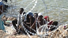 Libya güvenlik güçleri ve Kızılhaç çalışanları gıda yardımı dağıtırken göçmenler Libya-Tunus sınırına yakın bir bölgede, 23 Temmuz 2023