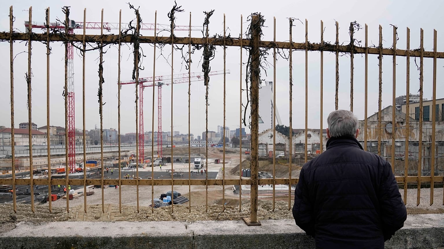 Um homem observa o estaleiro de construção da Aldeia Olímpica na antiga estação ferroviária de Porta Romana, em Milão, a 1 de março de 2023
