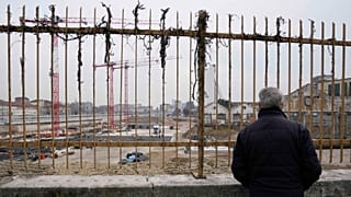 A man watches the construction site of the Olympic Village at the Porta Romana former railway yard, in Milan, 1 March 2023