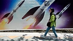 Μια γυναίκα περπατά μπροστά από ένα πανό που δείχνει την εκτόξευση πυραύλων, στη βόρεια Τεχεράνη του Ιράν.