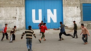 أطفال فلسطينيون يلعبون كرة القدم أمام بوابة مركز توزيع مساعدات غذائية تابع للأمم المتحدة في مدينة غزة، الجمعة 6 فبراير 2009.