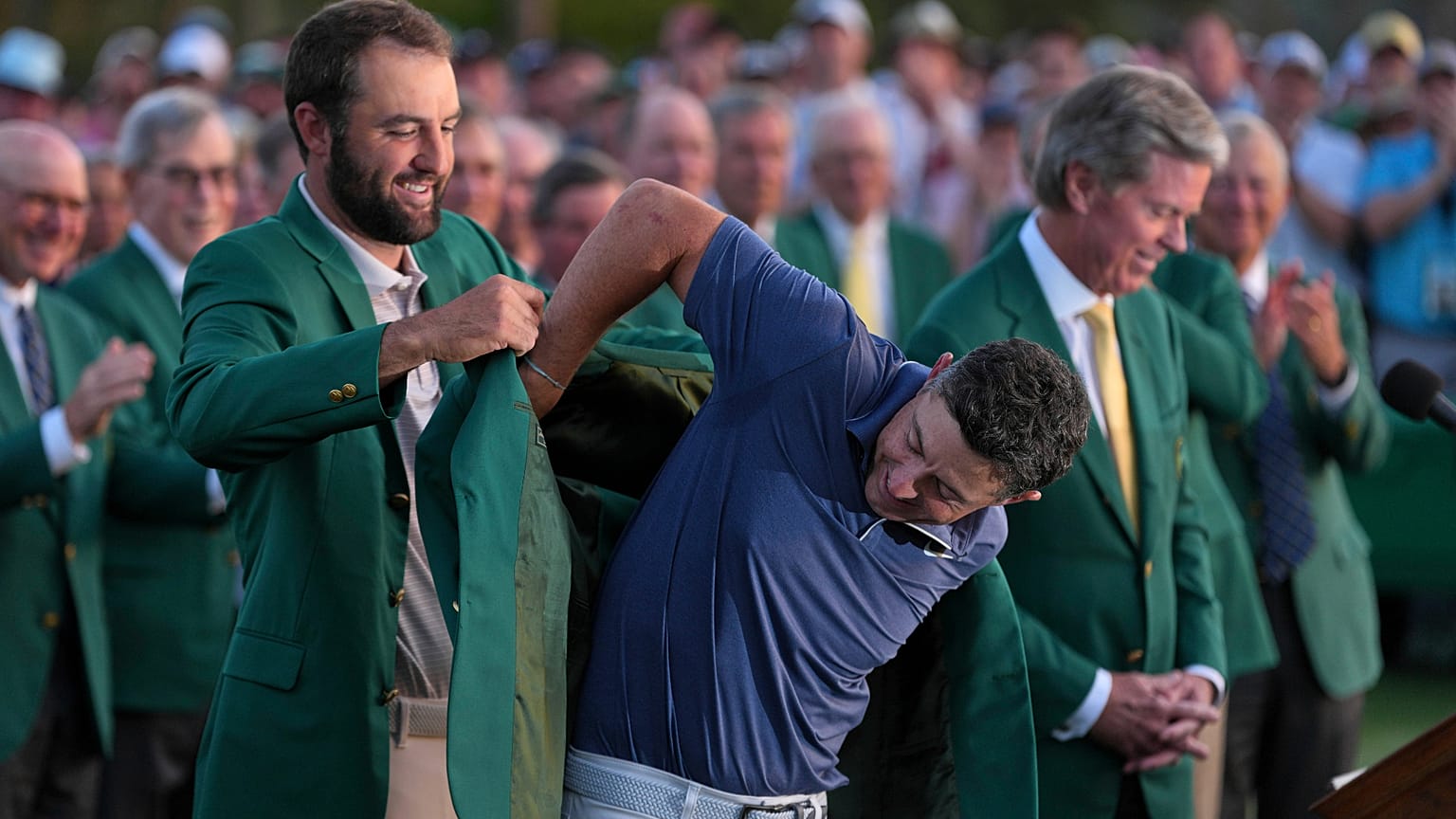 Scottie Scheffler puts the green Jacket on winner, Rory McIlroy, of Northern Ireland, at the Masters golf tournament, Sunday, April 13, 2025, in Augusta