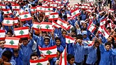 طلاب مدرسة في جنوب لبنان يلوحون بالعلم اللبناني