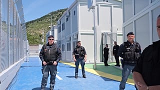 I poliziotti sorvegliano il centro di accoglienza per migranti, presso il porto di Shenjin, nel nord-ovest dell'Albania, mercoledì 5 giugno 2024.