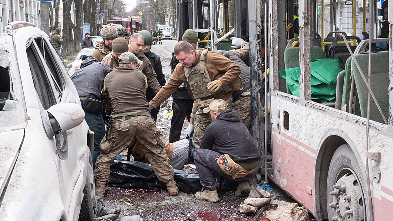 Ukrainische Soldaten tragen eine Leiche aus einem Trolleybus nach einem russischen Raketenangriff auf Sumy, Ukraine, Sonntag, 13. April 2025