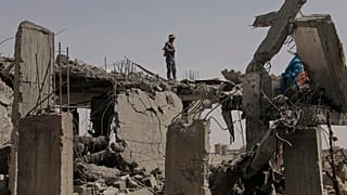 ضابط أمن حوثي يقف فوق حطام مبنى مدمر قيل إنه أصيب بغارات جوية أمريكية في صنعاء، اليمن، الاثنين، 7 أبريل/نيسان 2025. 