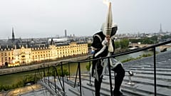 Un portador de la antorcha lleva la llama olímpica sobre un edificio a lo largo del río Sena en París, Francia, durante la ceremonia de apertura de los Juegos Olímpicos de Verano 2024, 26 de julio de 2024.