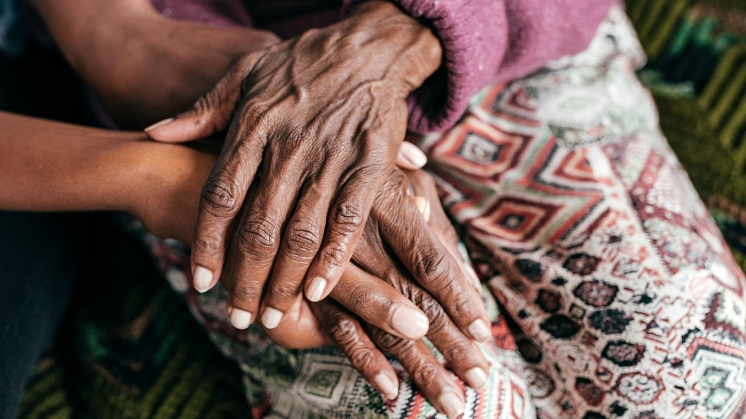 Una anciana y una joven se cogen de la mano.