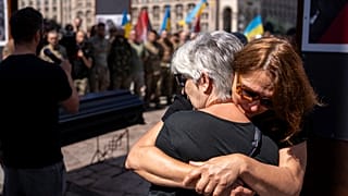 Des femmes s'étreignent lors de la cérémonie funéraire de Peter Fouche, 49 ans, tué le 27 juin lors de son travail dans l'est de l'Ukraine, sur la place principale de la ville de Kiev, en Ukraine.